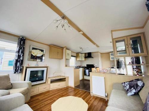 a living room with a couch and a tv and a kitchen at Cosy & Beautiful Charrot Caravan in Steeple