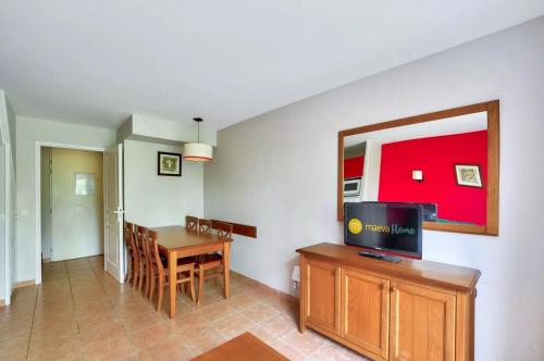 a living room with a table and a television on a cabinet at Residence du Lac - maeva Home in Monflanquin