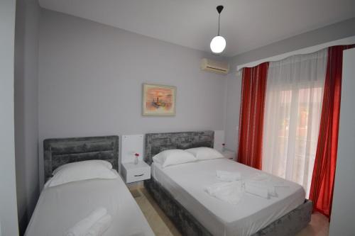 a bedroom with two beds and a window with red curtains at Little Cozy Apartment 1 in Sarandë