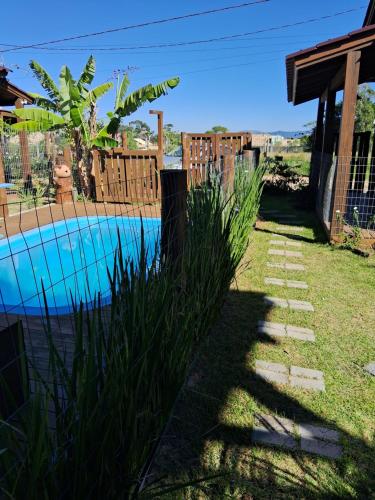 un patio trasero con piscina y valla en Chalés Praia do Rosa piscina compartilhada, en Imbituba