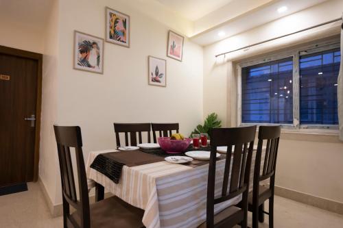 a dining room with a table and chairs and a window at Lakeside Suites in Kolkata