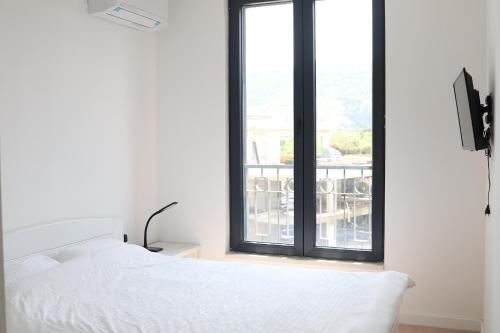 a bedroom with a white bed and a window at Trebinje Lux Apartment in Trebinje