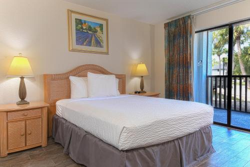 a bedroom with a large bed and a balcony at Legacy Vacation Resorts - Palm Coast in Palm Coast