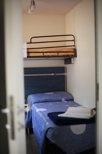 Una pequeña habitación con dos literas con sábanas azules. en LE TERRAZZE SUL GARDA RELAIS, en Biaza