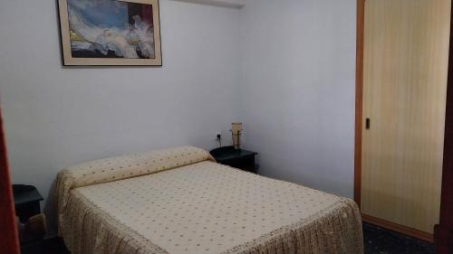 ein Schlafzimmer mit einem Bett und einem Bild an der Wand in der Unterkunft Apartamento pequeño frente al mar con piscina in Cullera