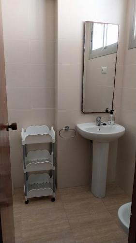 ein Bad mit einem Waschbecken und einem Spiegel in der Unterkunft Apartamento pequeño frente al mar con piscina in Cullera