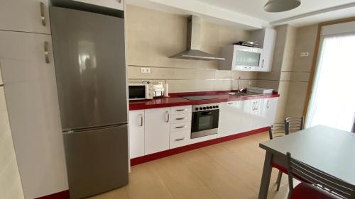 a kitchen with white cabinets and a stainless steel refrigerator at A Segunda Ronda in Melide