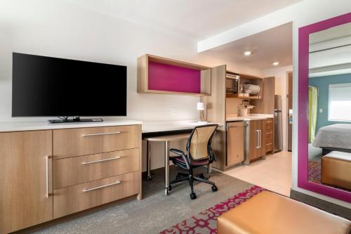 a hotel room with a desk with a tv and a bed at Home2 Suites by Hilton Bangor in Bangor
