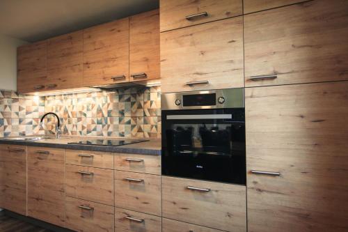a kitchen with wooden cabinets and a black oven at Apartma Gorski razgled in Srednja Vas v Bohinju