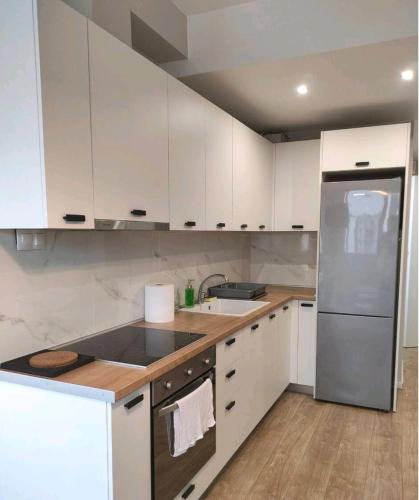 a kitchen with white cabinets and a stainless steel refrigerator at Antelope Studio 2 in Thessaloniki