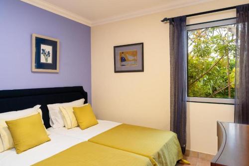 Un dormitorio con una cama con almohadas amarillas y una ventana en Oceano Azul en Porto Santo