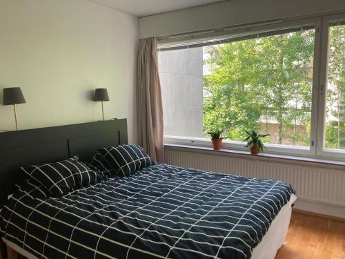 een slaapkamer met een bed en een groot raam bij Tapiola Hill Apartment 2 bedroom and 1 living with private parking in Espoo