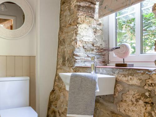 a bathroom with a sink and a stone wall at Sandpiper Cottage in Salcombe