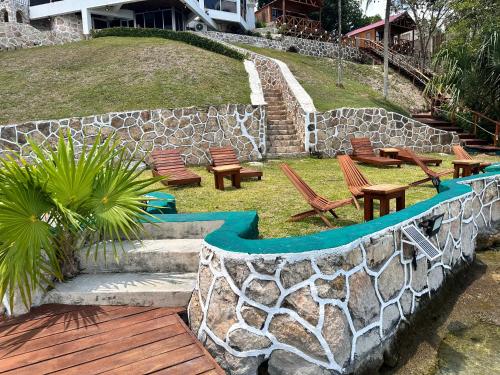 a stone retaining wall with chairs and benches in a yard at bacalar My Love Front Laguna in Bacalar