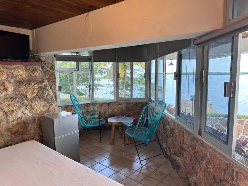 a kitchen with chairs and a table and windows at bacalar My Love Front Laguna in Bacalar