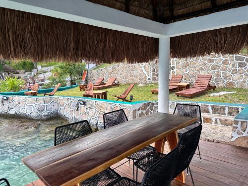 a wooden table and chairs on a patio with a pool at bacalar My Love Front Laguna in Bacalar