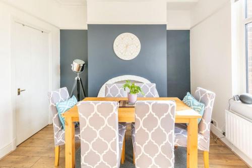 a dining room with blue walls and a wooden table and chairs at Atrium House in Hazel Grove
