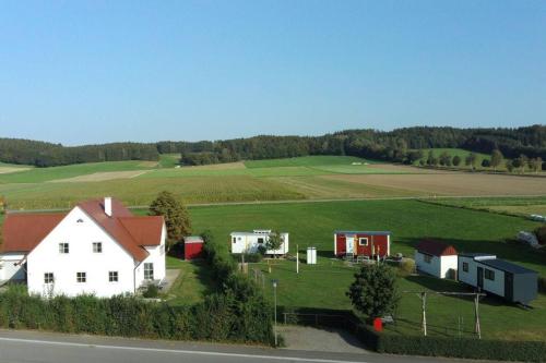 une maison blanche avec un toit rouge dans un champ vert dans l'établissement Feriendörfle Fritz - Zirkuswagen (rot), à Ettenbeuren
