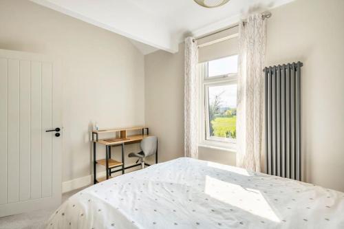a white bedroom with a bed and a window at Atrium House in Hazel Grove