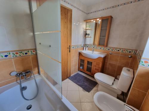 a bathroom with a toilet and a sink and a tub at Casa Pedra da Nau- 2 bedroom APT @Figueira da Foz in Buarcos