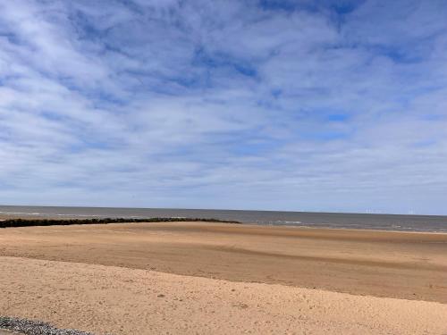 an empty beach with a blue sky and the ocean at The Nest in Prestatyn