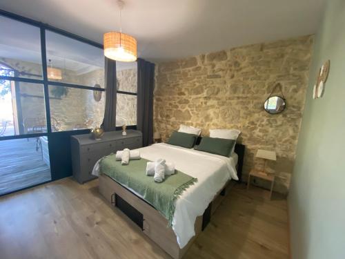 1 dormitorio con cama y pared de piedra en Gîte « domaine de l’oustal nau », en Peyriac-de-Mer