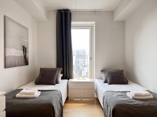 two beds in a small room with a window at Modern Spacious 3 Bedroom Apartment At Richard Mortensens Vej With Balcony Close To The Royal Arena And Fields in Copenhagen