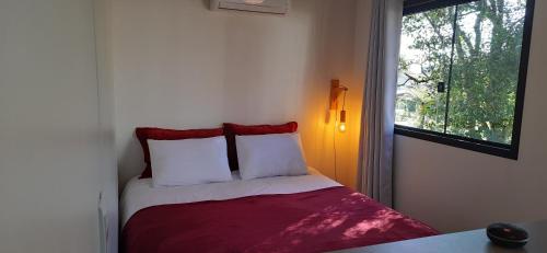 1 dormitorio con 1 cama con 2 almohadas y ventana en Recanto das Gralhas en São Francisco de Paula