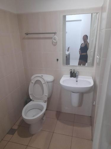 a woman taking a picture of a bathroom with a toilet and sink at Roxas Blvd Stunning Studio Condo Near US Embassy in Manila