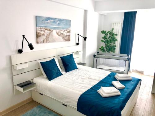 a bedroom with a large bed with blue pillows at Veli Apartments 348 Infinity in Mamaia Sat/Năvodari