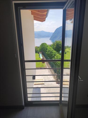 a door to a balcony with a view of the water at Luminoso appartamento vista lago in Solto Collina