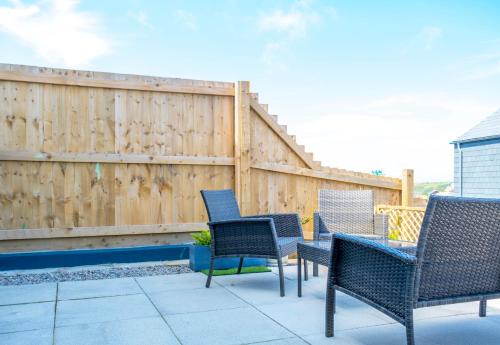 a patio with four chairs and a fence at The Waves in Newquay