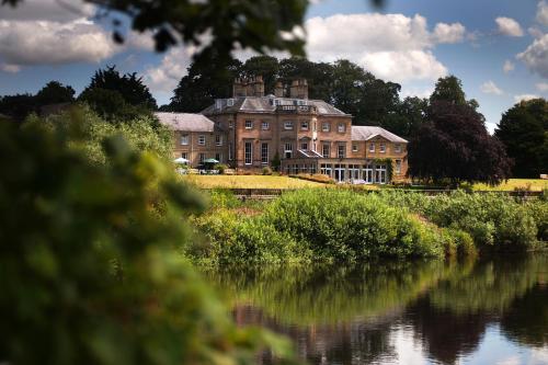 a large house on a hill next to a river at Ednam House Hotel in Kelso