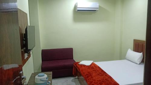 a small room with a bed and a chair at Shagun Banquet and Hotel in Gwalior