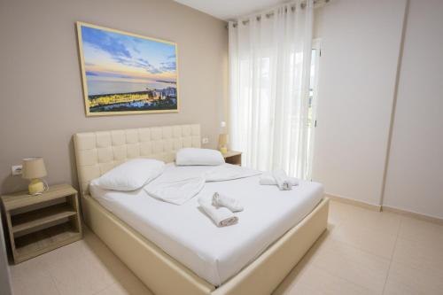 a white bedroom with a large bed with white sheets at Jordan`s Hotel in Vlorë