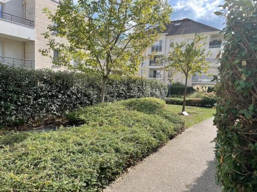 una pasarela frente a un edificio con árboles y arbustos en Studio 28 m2 & jardin privatif 20 m2 en Montigny-le-Bretonneux