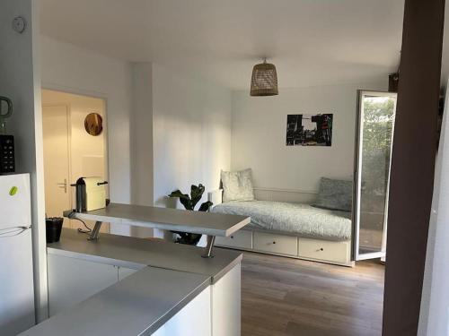 Il dispose d'une cuisine et d'un salon avec un canapé et une table. dans l'établissement Studio 28 m2 & jardin privatif 20 m2, à Montigny-le-Bretonneux