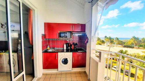 uma cozinha com armários vermelhos e uma máquina de lavar roupa em Studio T1 bis La Belle Vue, vue mer, wifi, plage à 50m em Le Moule