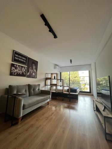 a living room with a couch and a large window at Studio GreenHaus - Pileta - Gym - Sauna in Buenos Aires