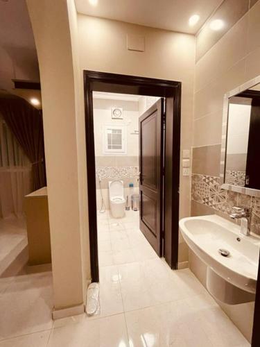 uma casa de banho com um WC, um lavatório e uma porta em شقق الأجواء الفاخرة em Medina