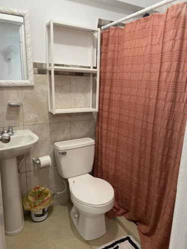 y baño con aseo, lavamanos y cortina de ducha. en Gavidias Guest House, en San Lorenzo
