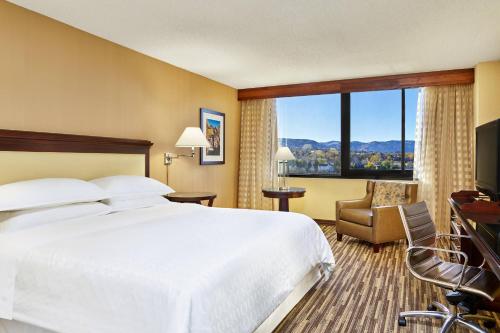 een hotelkamer met een bed en een groot raam bij Sheraton Denver West Hotel in Lakewood