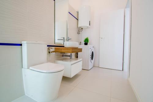 a white bathroom with a toilet and a sink at Forest by the sea in Jupiter