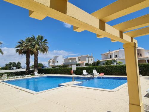 een zwembad in een resort met stoelen en bomen bij Mar a Vista in Albufeira