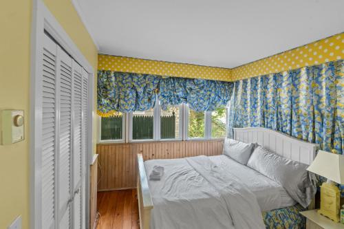 1 dormitorio con 1 cama con cortinas azules y amarillas en The Hampton Sack, en East Hampton