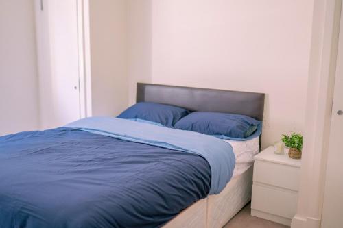 een bed met blauwe lakens in een witte slaapkamer bij Flat in London in Londen