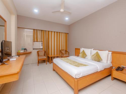 ein Hotelzimmer mit einem Bett, einem Schreibtisch und einem TV in der Unterkunft Hotel Ashok Tuliip Bhiwandi in Thane