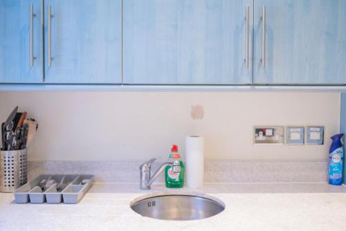 a kitchen counter with a sink and blue cabinets at Flat in London in London
