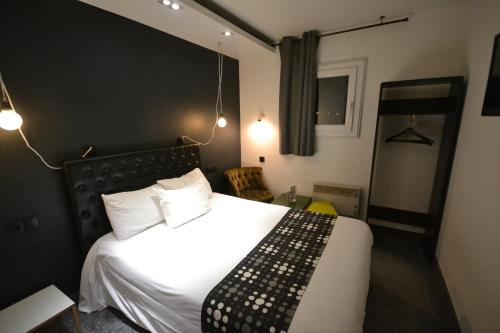 a bedroom with a white bed with a black headboard at Brit Hotel Baillet-en-France in Baillet-en-France