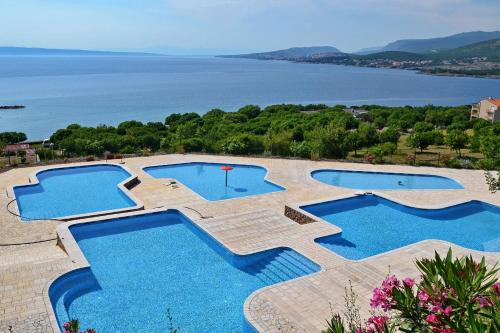 un grupo de tres piscinas con el océano en el fondo en Mobile home Nebo Luxus, en Klenovica